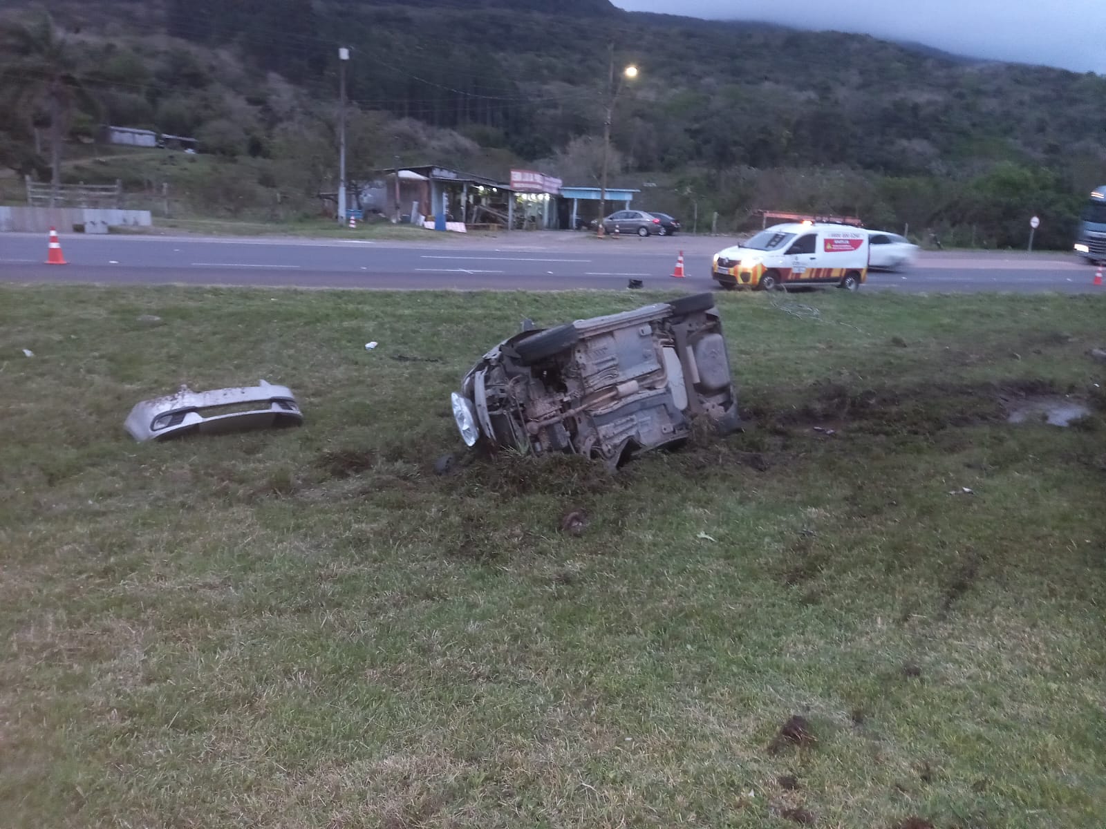 Carro sai da pista, atinge poste e tomba na BR-101, em Osório